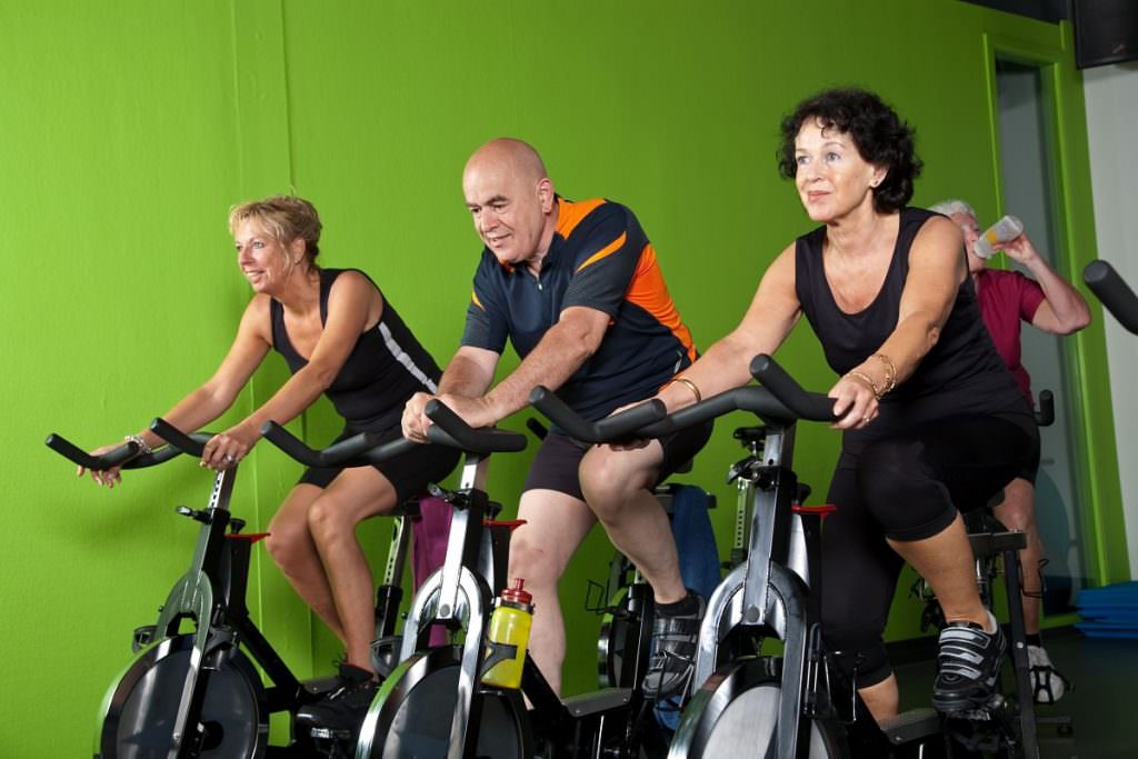 Three people on indoor cycles