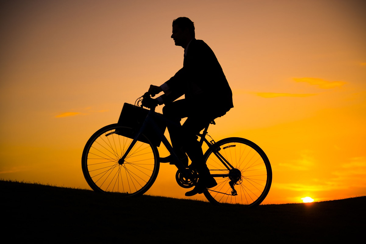 Business man riding bike on the hill