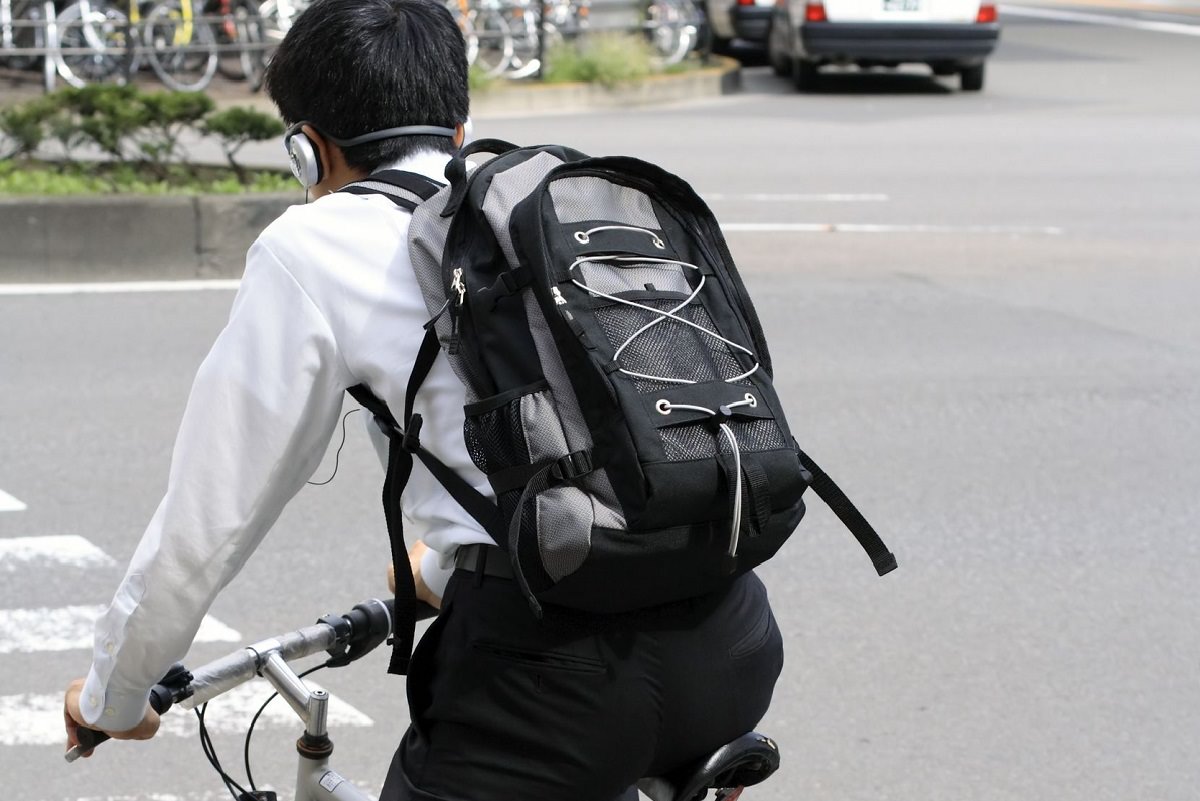 Young man with headphones on, riding a bike