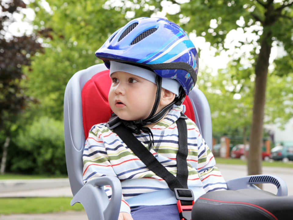 Child sitting by bicycle with crash helmet