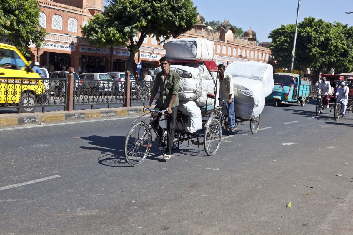 Man cycling a rickshaw with loaded cargo