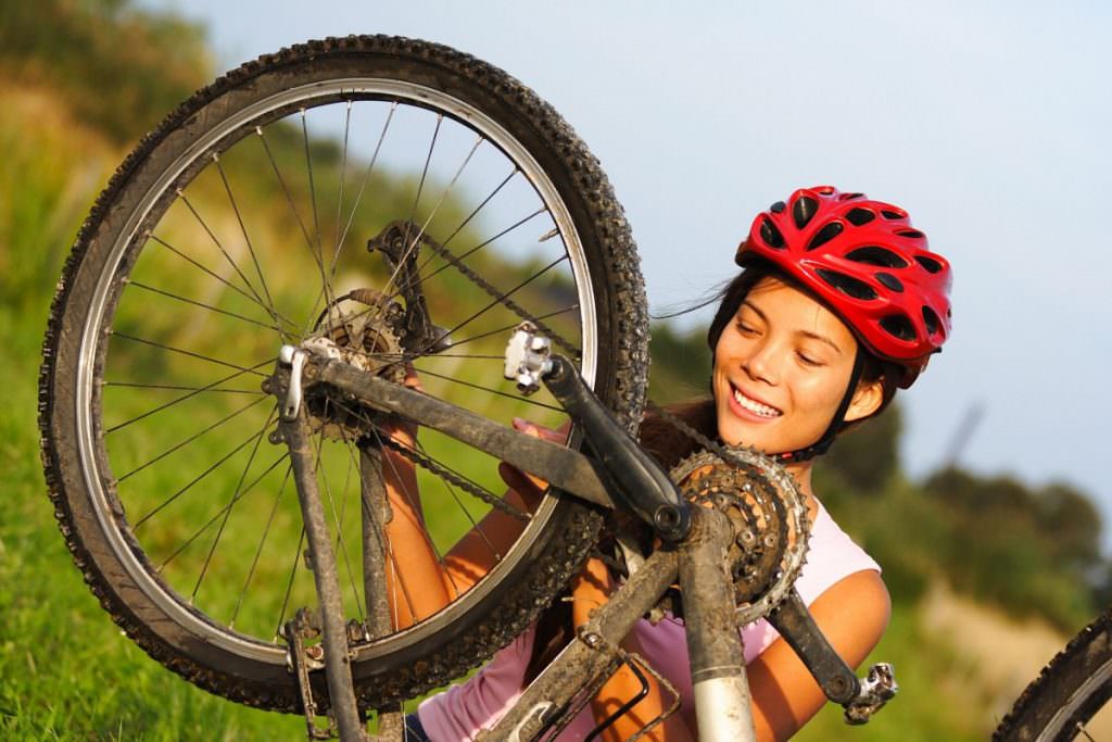 Woman fixing mountain bike wheel