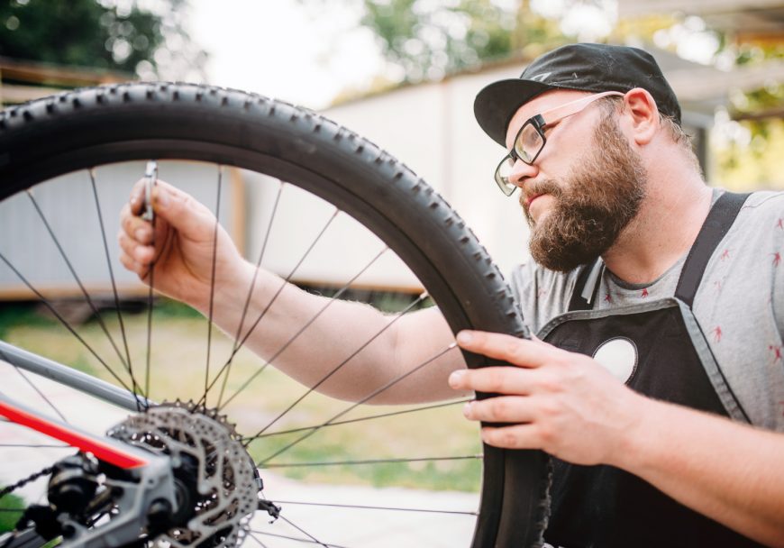 Bicycle Mechanic Adjusts Bike Spokes