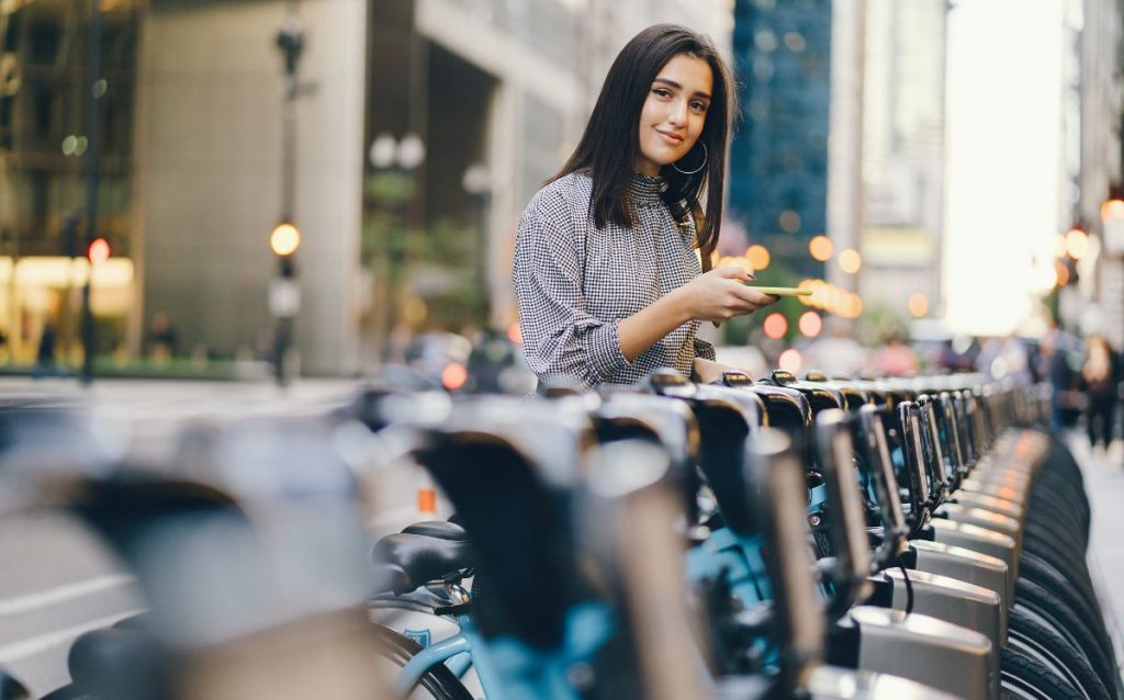 Girl Standing At Bike Sharing Stand