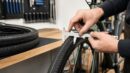 Mechanic measuring a bicycle tire sidewall for tire size conversion.