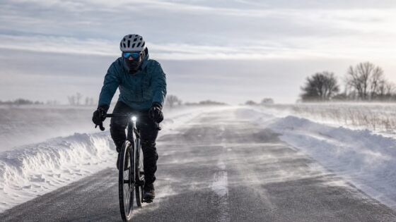 Winter cyclist riding into cold wind while wearing layered cold-weather gear.