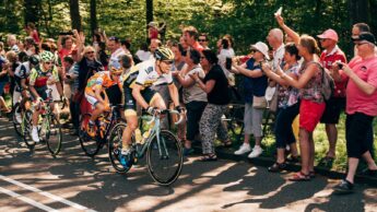 Road cyclists racing past spectators during a stage race.