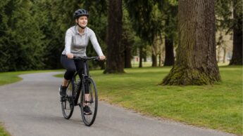 A beginner cyclist rides calmly on a quiet paved park path.