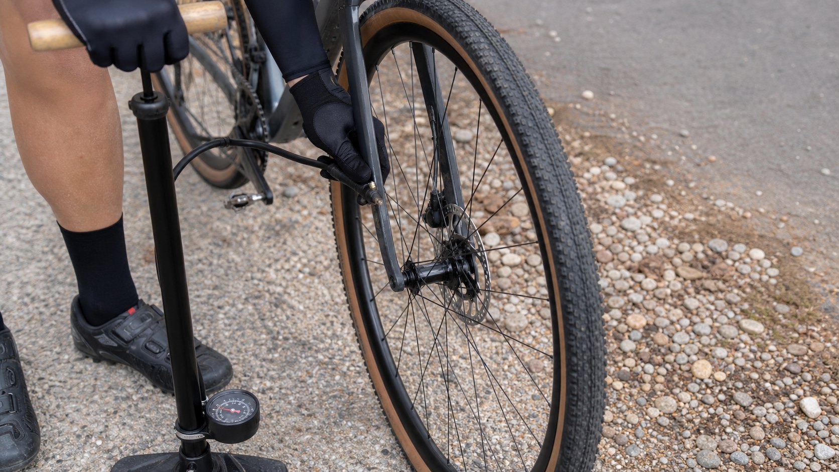 Bike tire being inflated with a floor pump before riding on mixed pavement and gravel.