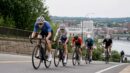 A group of road cyclists climbing on an urban race course during a summer championship.