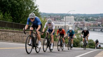 A group of road cyclists climbing on an urban race course during a summer championship.