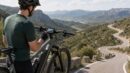 Cyclist viewing ride data on a display while stopped on a mountain road.