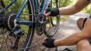 A rider puts a dropped bike chain back onto the chainring by hand.
