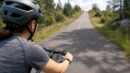 A beginner cyclist shifts gears while riding on a quiet paved path.