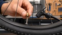 A small brass Presta valve adapter attached to a bicycle valve beside a floor pump.
