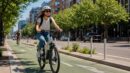 A rider on an electric bicycle in a protected city bike lane.