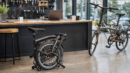 A folded commuter bike in a modern bike shop used as an editorial visual for Brompton partnership coverage.